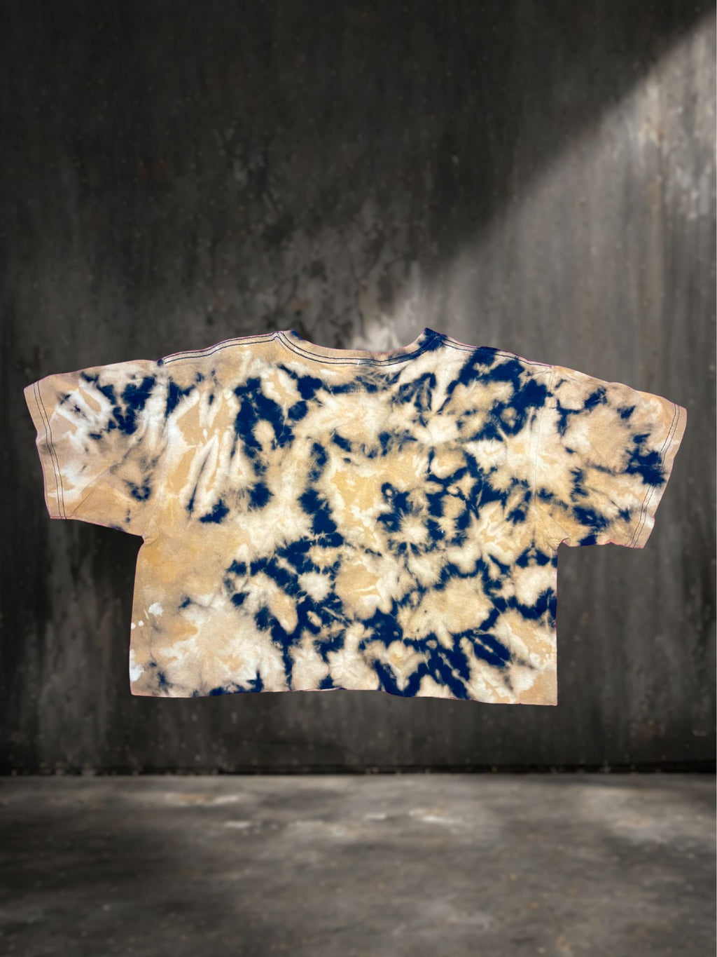 Tie-dye t-shirt with blue and beige pattern on a dark background