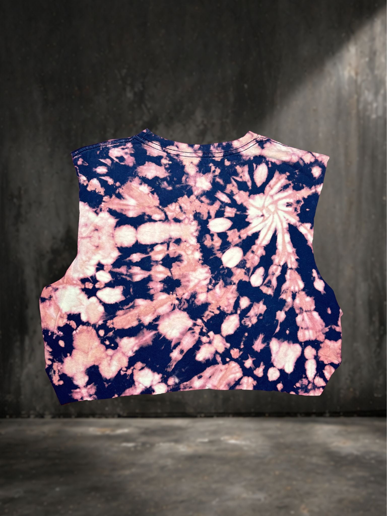 Tie-dye patterned sleeveless crop top on a dark background