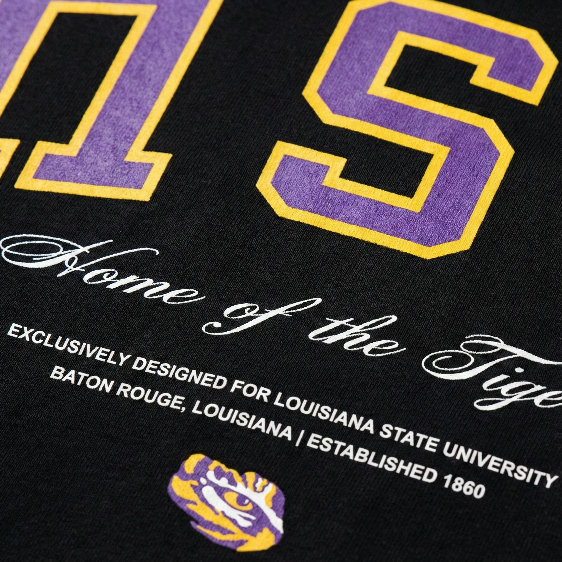 Black shirt with purple and gold text and logo, featuring 'Home of the Tigers' and LSU branding.