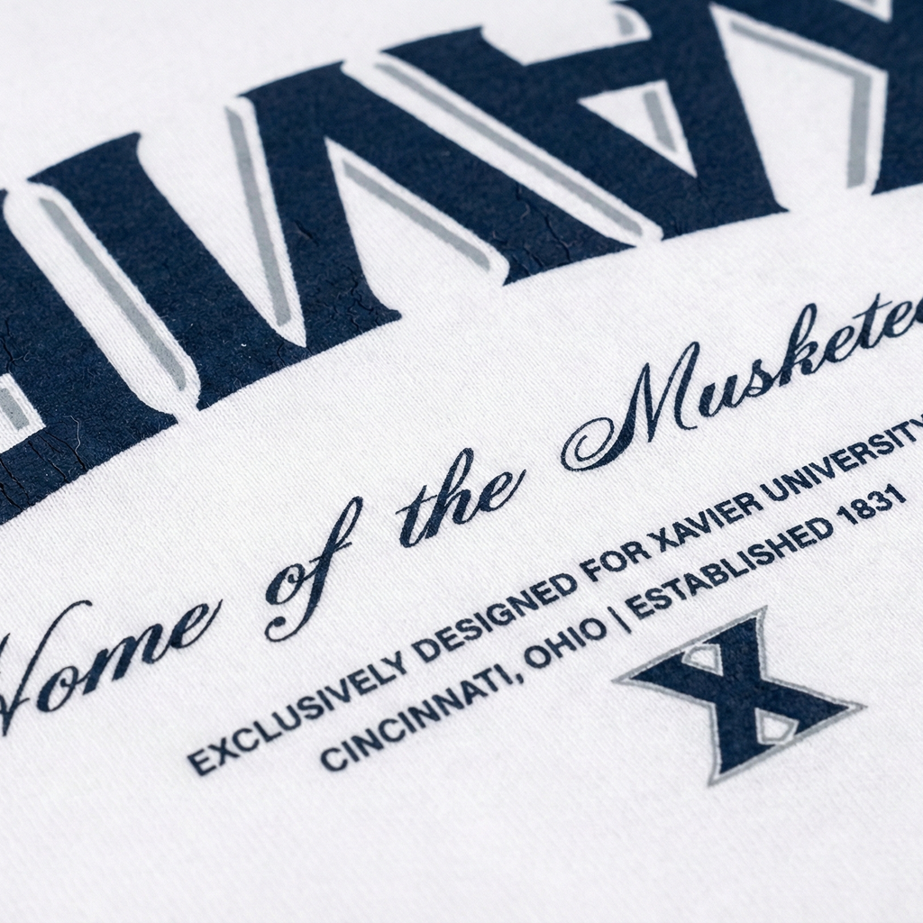 Close-up of a shirt with 'Home of the Musketeers' text and Xavier University logo.