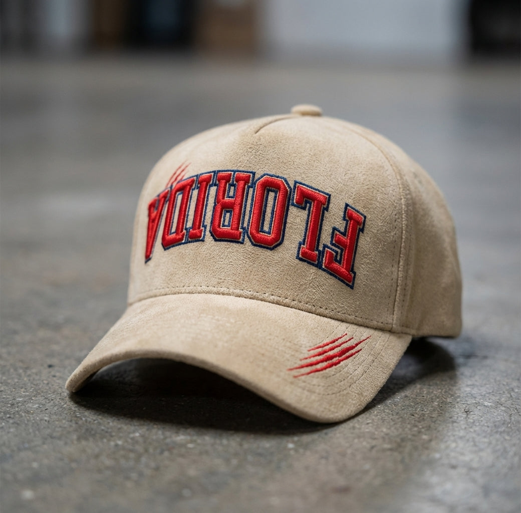 Beige cap with 'FLORIDA' embroidered upside down in red and blue on a concrete floor.