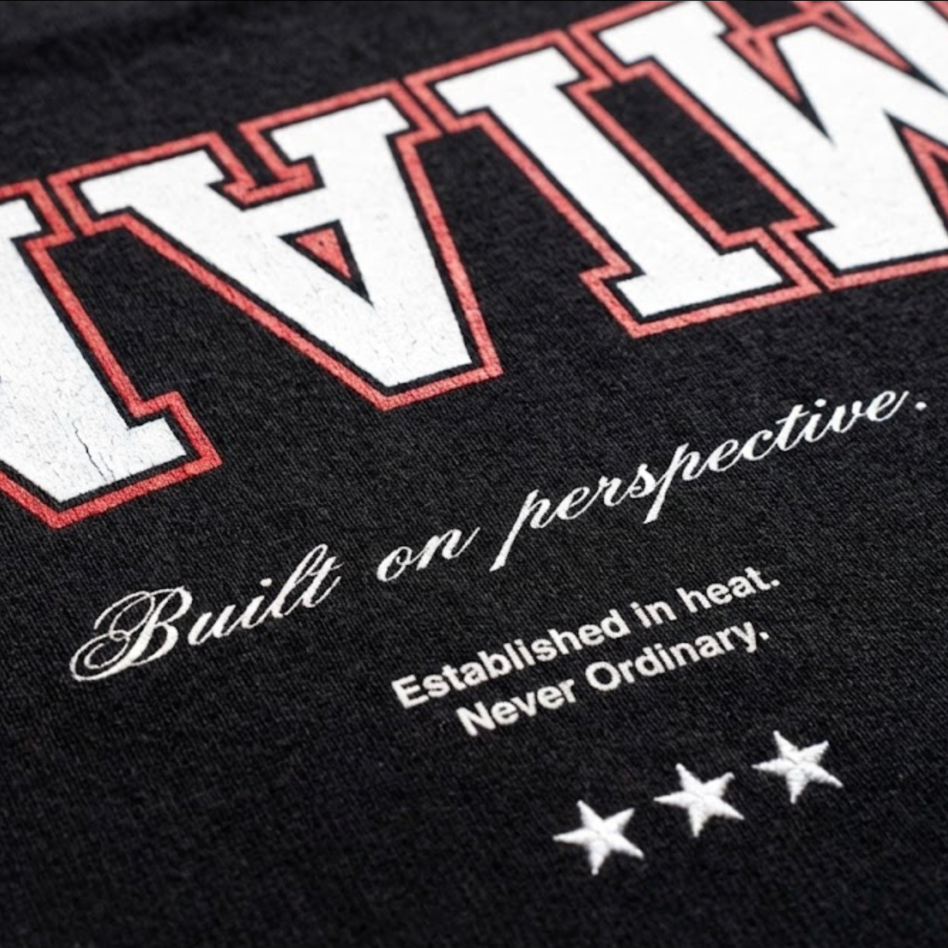 Black t-shirt with white and red text and star design on a black background